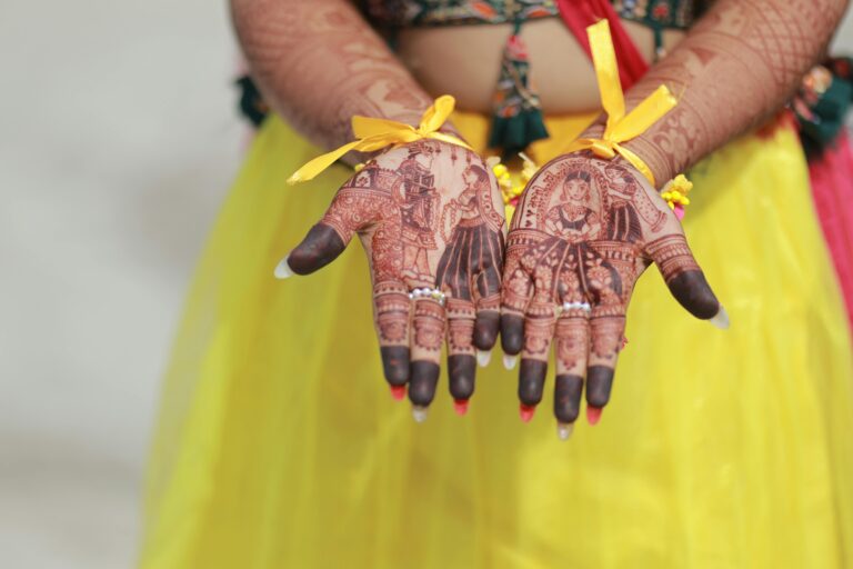 Beautiful henna mehndi art on a bride's hands adorned with yellow ribbons, showcasing traditional wedding design.