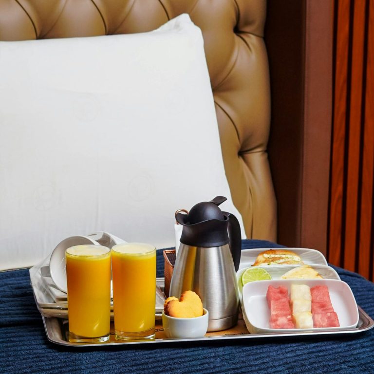 Cozy hotel room breakfast with juice, fruit, and coffee on tray.
