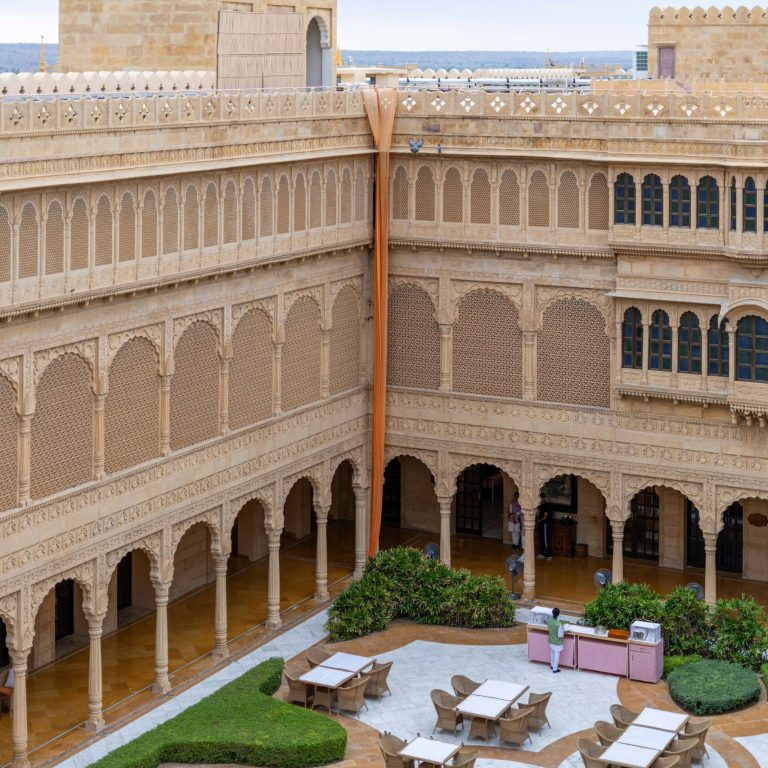 Explore the intricate sandstone architecture of a Jaisalmer heritage hotel courtyard.
